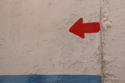 Old structured wall with a blue stripe and red arrow showing the direction left.