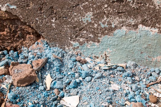 Detail of a broken wall with stones painted blue.