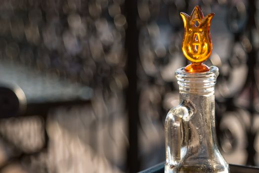 On the balcony of a restaurant, full of sunlight, jar with an olive oil. Yellow flower decoration.