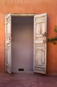 Old door from a roof, both sides opened. Orange facade contrasting with the color of the door.