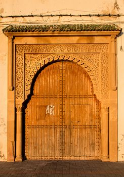 Wooden gate in a traditional style in Essaouira. Decorated frame. Enlightened by evening sunlight.