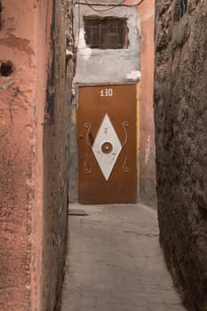 Old small street in Marrakesh. Brown door with white decoration.