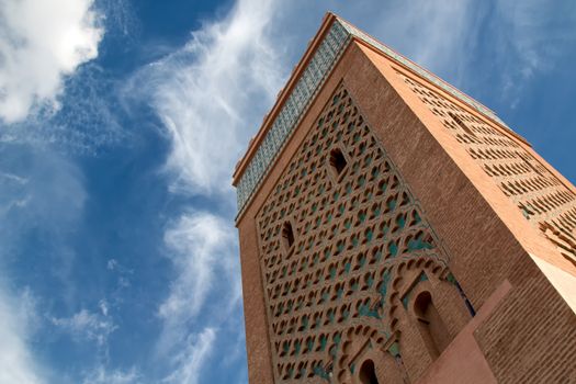 Tower of a famous mosque in medina of Marrakesh. Traditional details of the arabian architecture. Cloudy sky.