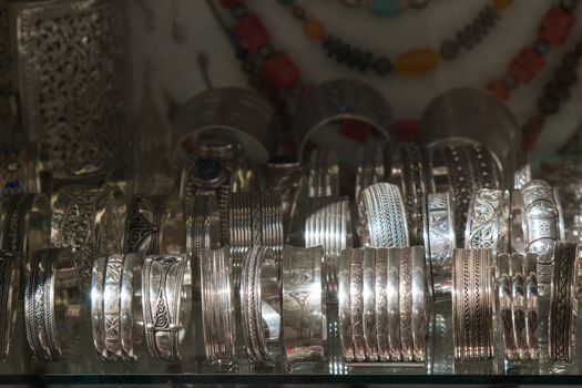 Silver engraved traditional bracelets in moroccan shop. Necklaces in the background.