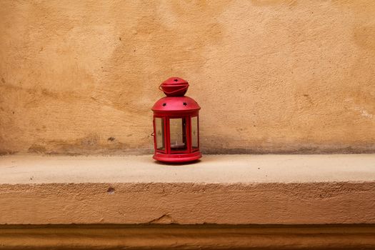 Lantern on the step with a background of a facade of a house. Waiting for the evening to lighten the place.