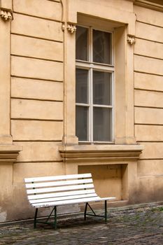 Yard of an old house. Empty white bench.