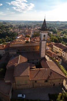 Top view of Vinci Village around meadow area from Conti Guidi Castle in Italy, under bright blue sky background.