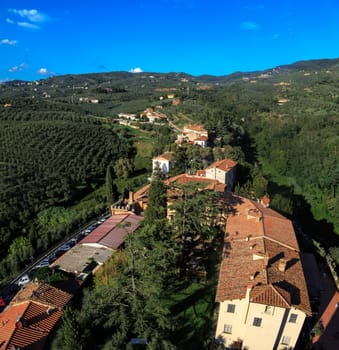 Top view of Vinci Village around meadow area from Conti Guidi Castle in Italy, under bright blue sky background.