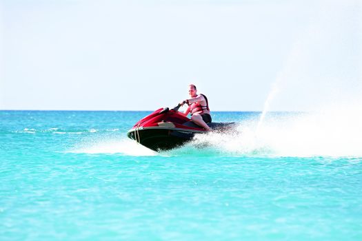 Young guy cruising on a jet ski on the caribbean sea