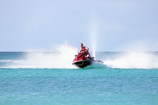 Young guy cruising on a jet ski on the caribbean sea