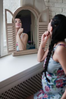 Pregnant woman looks the mirror