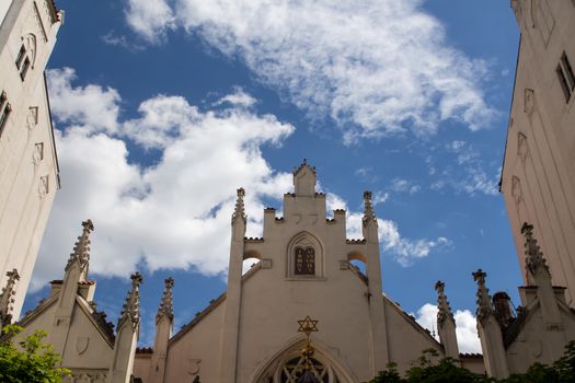 Neo gothic building of a jewish synagogue in Prague. Blue sky with many contrasting white clouds.