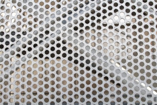 Detail of a iron plate with perforated circle pattern. Next structure in the background.