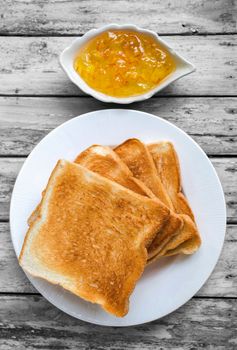 Slices of toast bread with orange jam on gray wood background