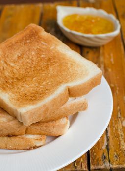 Slices of toast bread with orange jam on wood background