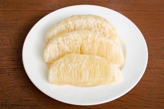 Thai pomelo fruit Peeled in white dish on wood table.