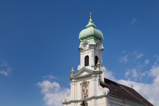 View on the facade of St. Elizabeth church. Baroque details, tower with clock and green roof. Blue sky with white clouds.