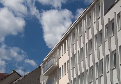 Detail of a modern building. Contrast bright blue sky with white clouds.