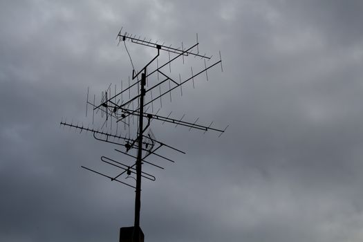 Silhouette of a big antenna. Cloudy rainy grey sky in the background.