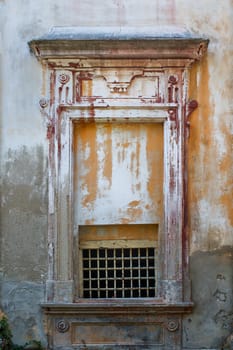 Old walls of an abandoned manor-house. Decorative window, part of facade, just with small grid to get the air inside.