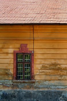 Old wall of an abandoned manor-house with a stylish window. Part of an orange roof.