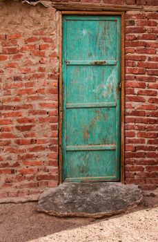 Old but still bright green door. Entrance to a bedouin house in a village in the desert in Egypt. House made of bricks.