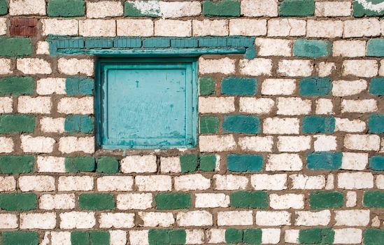 Contrast details of the bricks of a small mosque in the desert in Egypt. Green closed window.