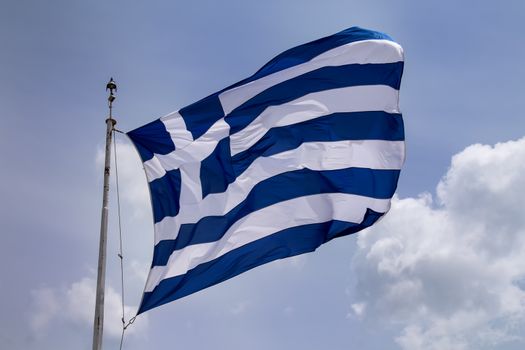 Greek flag blowing in the wind. Cloudy sky in the background.