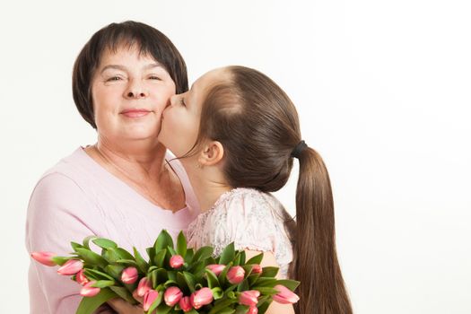 the granddaughter kisses the grandmother and gives it flowers