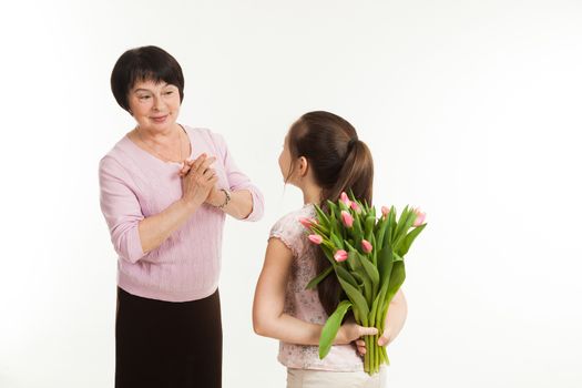 the granddaughter hides a bouquet of flowers for the grandmother behind the back