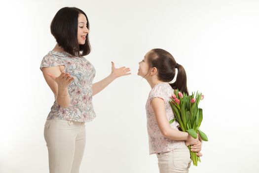 the girl hides a bouquet of flowers for mother behind the back