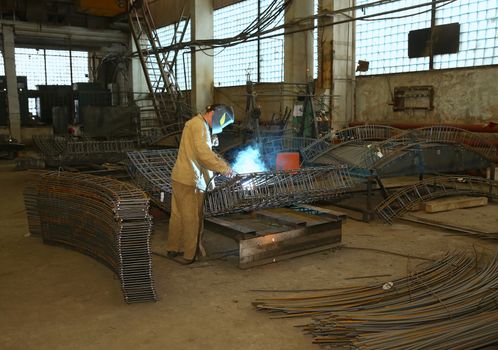 Welder in factory. Worker weld metal in factory and sparks