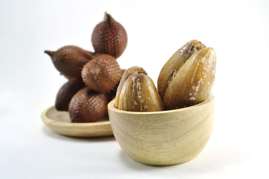 Ripped fresh Zalacca on little wooden bowl with a blurry cluster of zalacca on white background