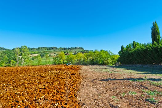 Tractor Plowing Field on a Background of Vineyards in Tuscany, Italy