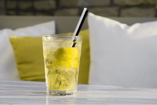 yellow cocktail mojito with straws on a white table on the background of pillows