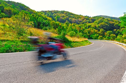Motion Blur Motorcyclist on the Winding Asphalt Road in the Italian Alps
