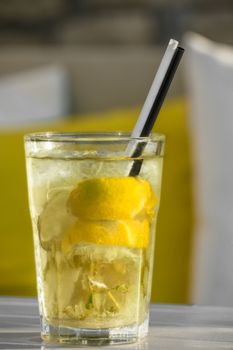 yellow cocktail mojito with straws on a white table on the background of pillows