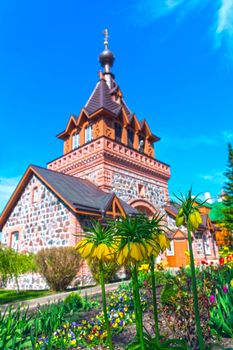 Spring blooming tulips against the background of the brick Orthodox Church