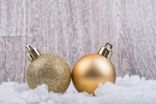 Two christmas balls on the snow with wooden background