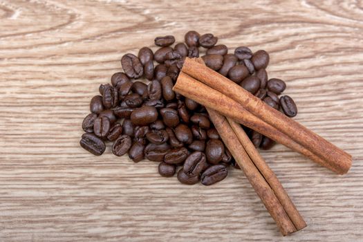 Grains of coffee with cinnamon on a wooden background