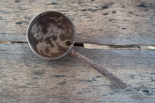 Old coconut shell spoon on wooden desk.