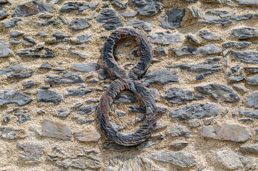 Old castle stone wall with the letter 8 made of wrought iron. texture background.