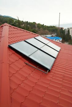 Solar water heating system (geliosystem) on the red house roof.