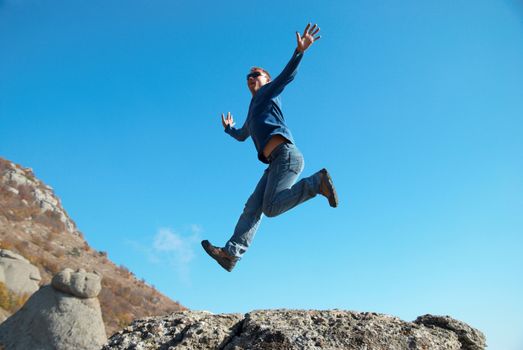 Man jumping on the rocks with landscape background