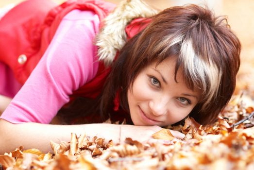 Beautiful girl's portrait with leaves in the autumn park