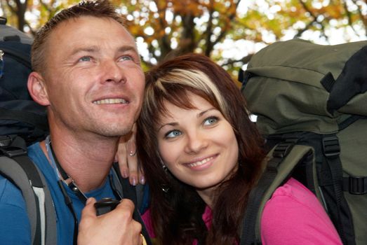 Young tourist couple in the autumn park with rucksacks