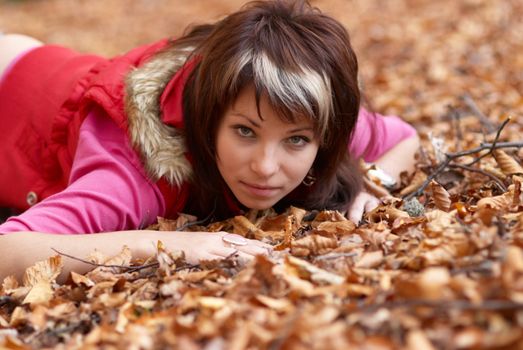 Beautiful girl's portrait with leaves in the autumn park