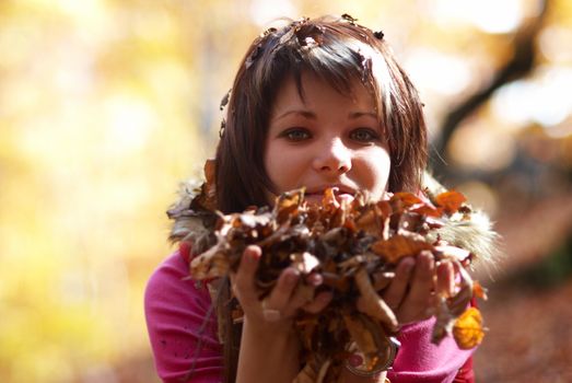 Beautiful girl's portrait with leaves in the autumn park