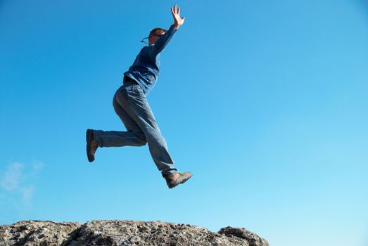 Man jumping on the rocks with landscape background