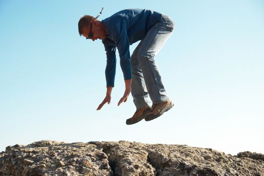 Falling down man from the rock with blue background